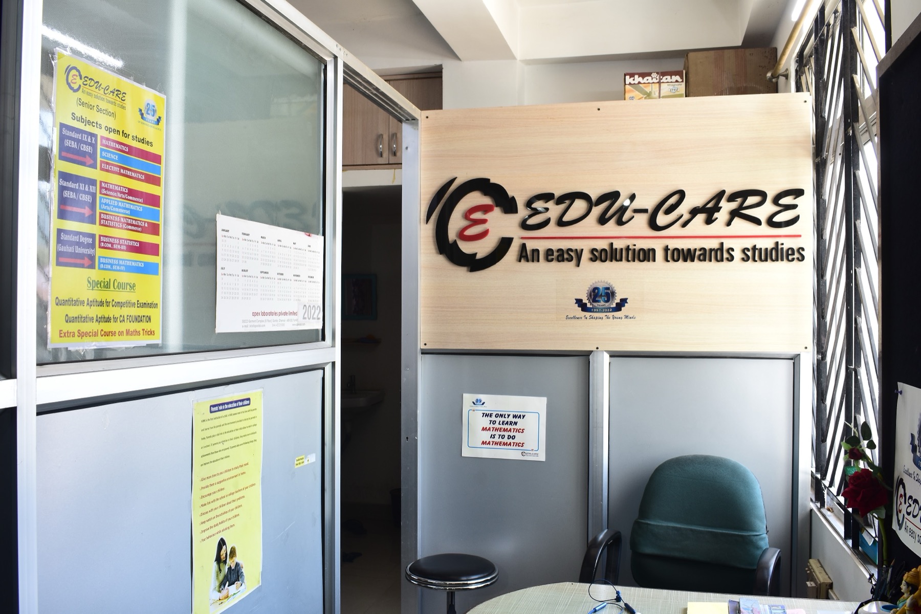 The EDU-CARE office, with the company sign on a wooden panel, posters on the glass and a green chair